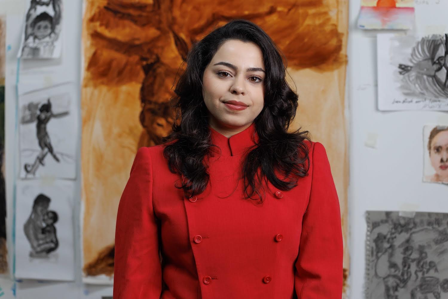 Artist Malak Mattar - she has long brown hair and is wearing a bright red jacket