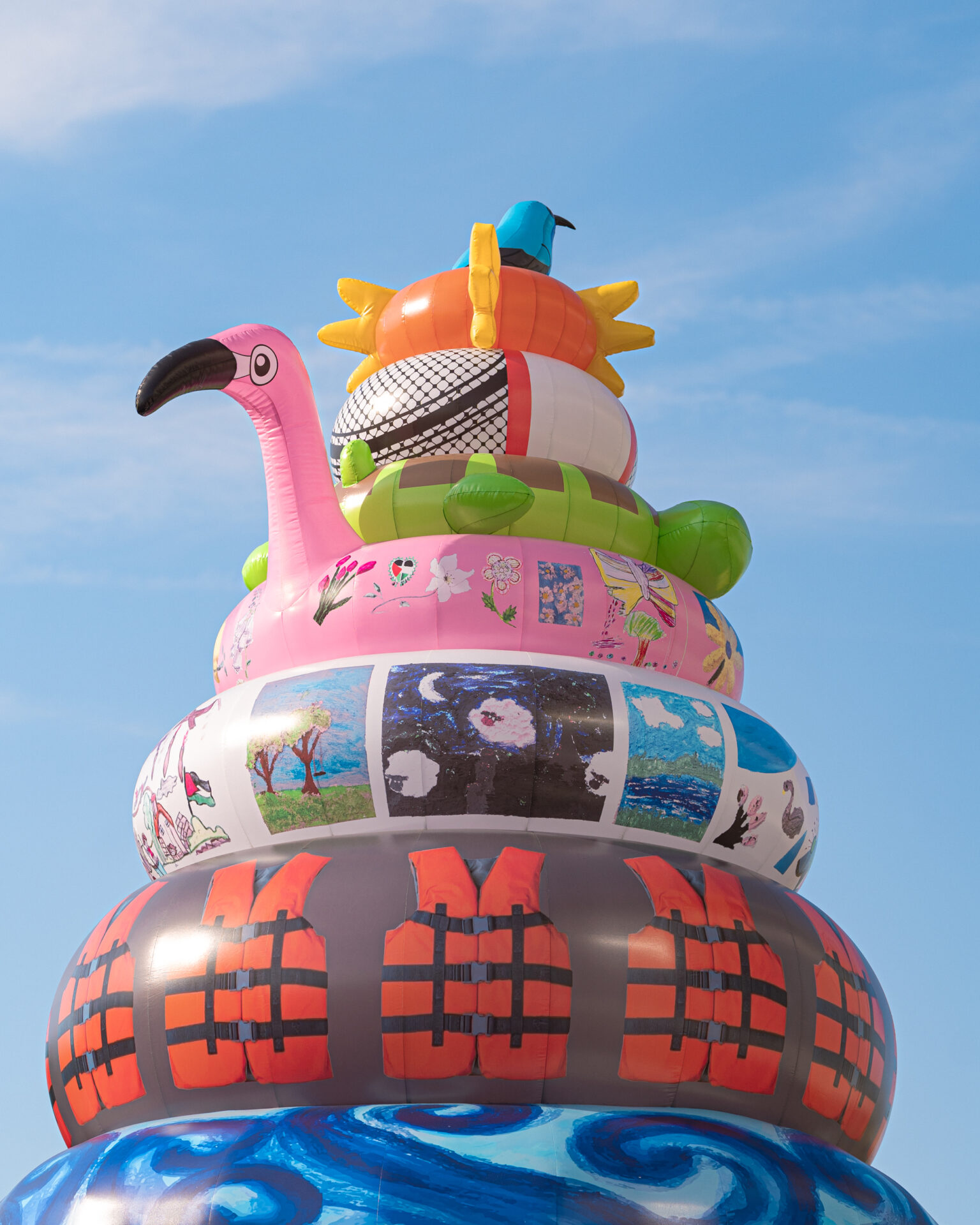 large inflatable sculpture of rubber rings featuring images by palestinian children and a sun bird on top