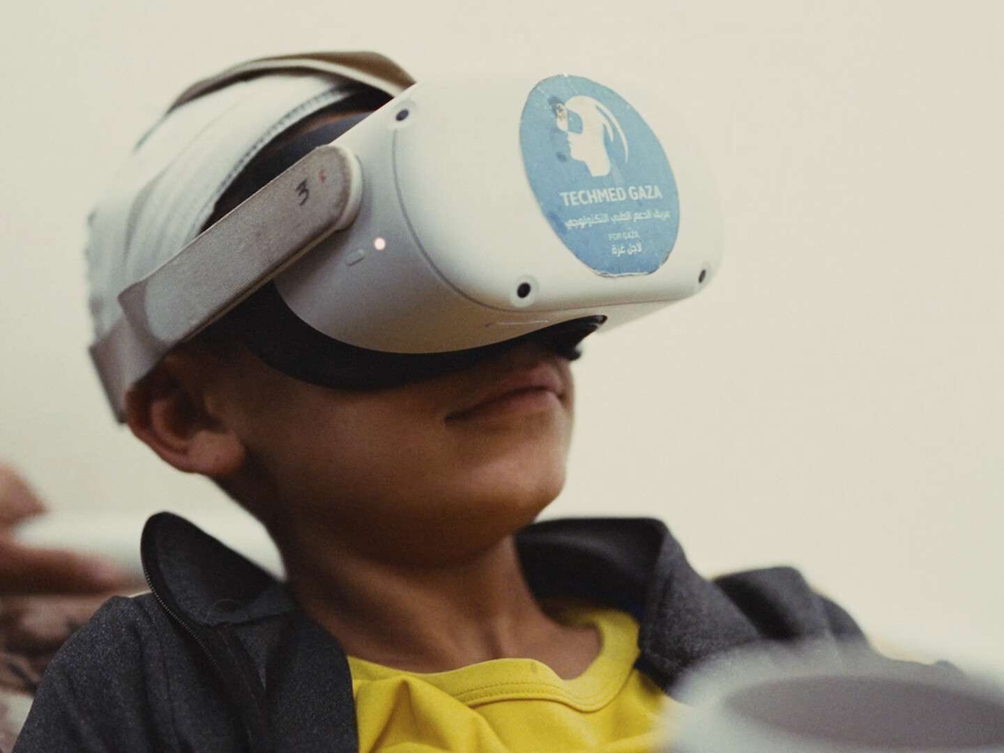 Rendered-in-Light-edited Image of a child in Gaza wearing a VR headset